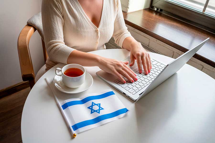 Девушка за ноутбуком возле флага Израиля, где работа доступна для иностранцев