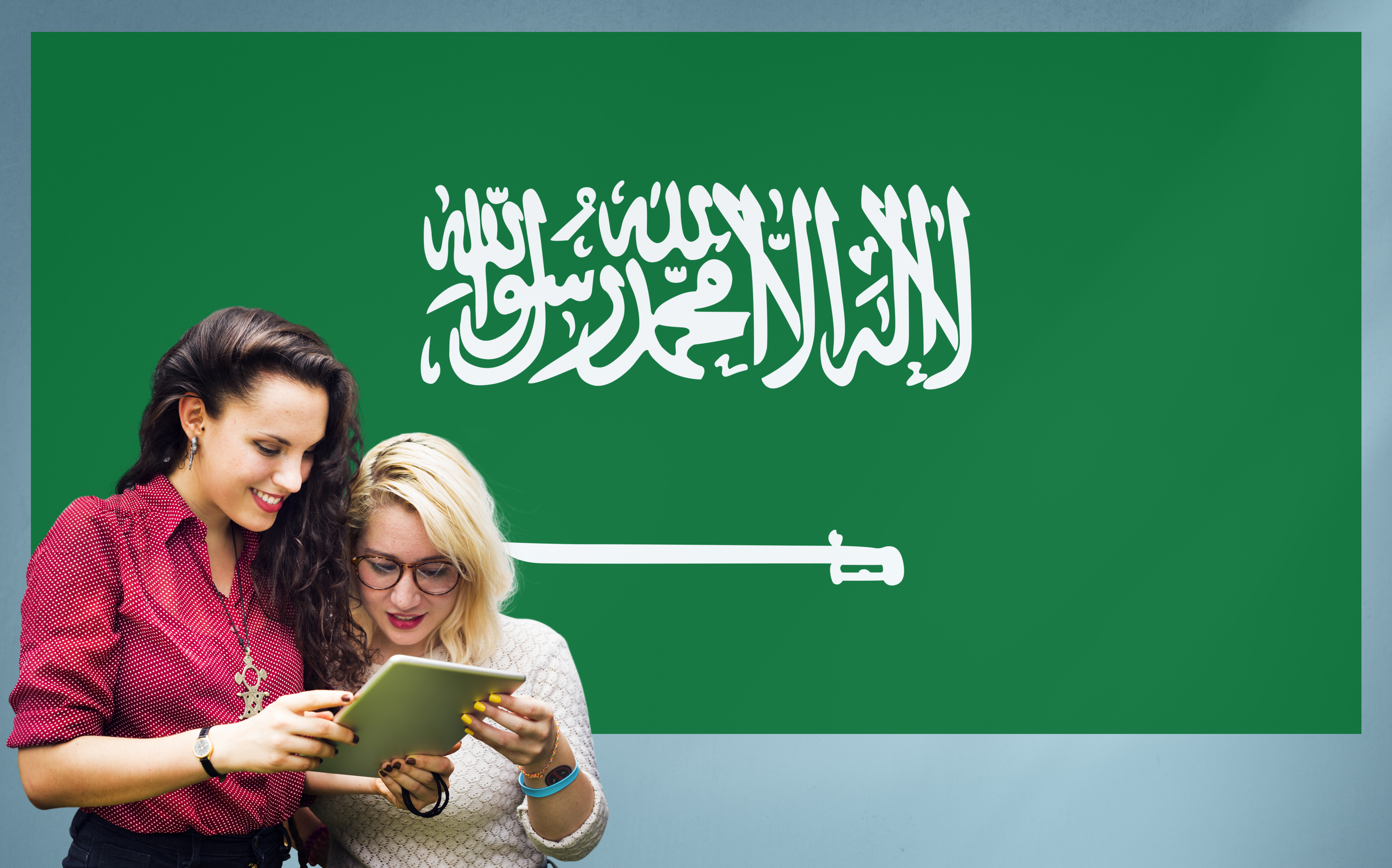 Студентки на фоне флага Саудовской Аравии, куда могут уехать на учебу иностранцы